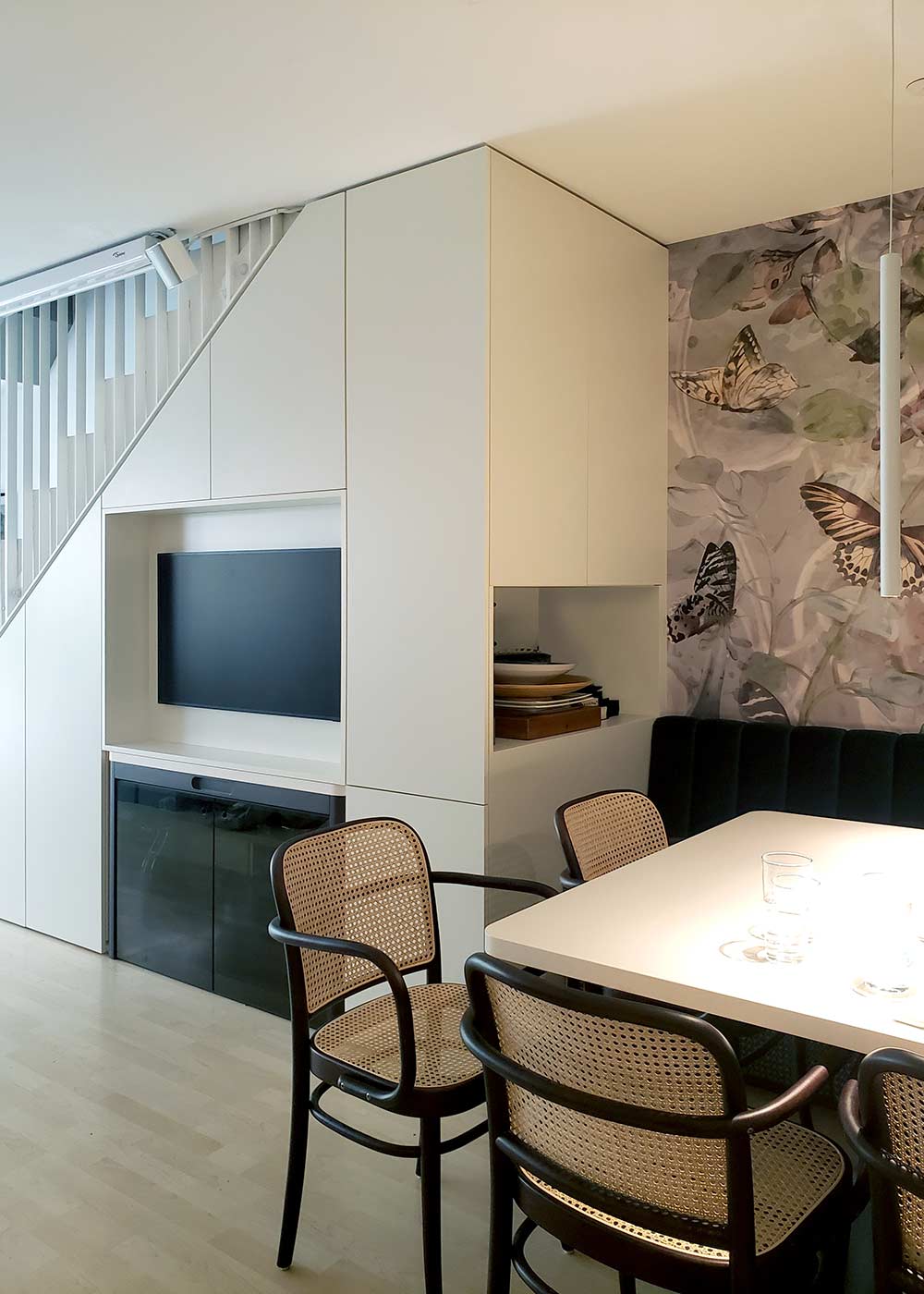 Wohnwand unter der Treppe mit TV-Nische und Stauraum.